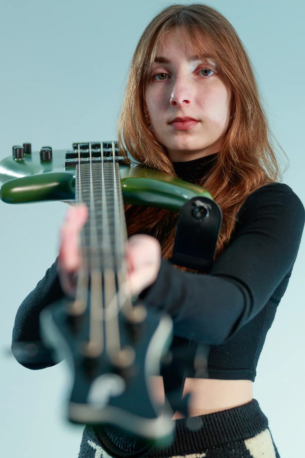 Close portrait of Tori Morley behind the neck of a green bass.