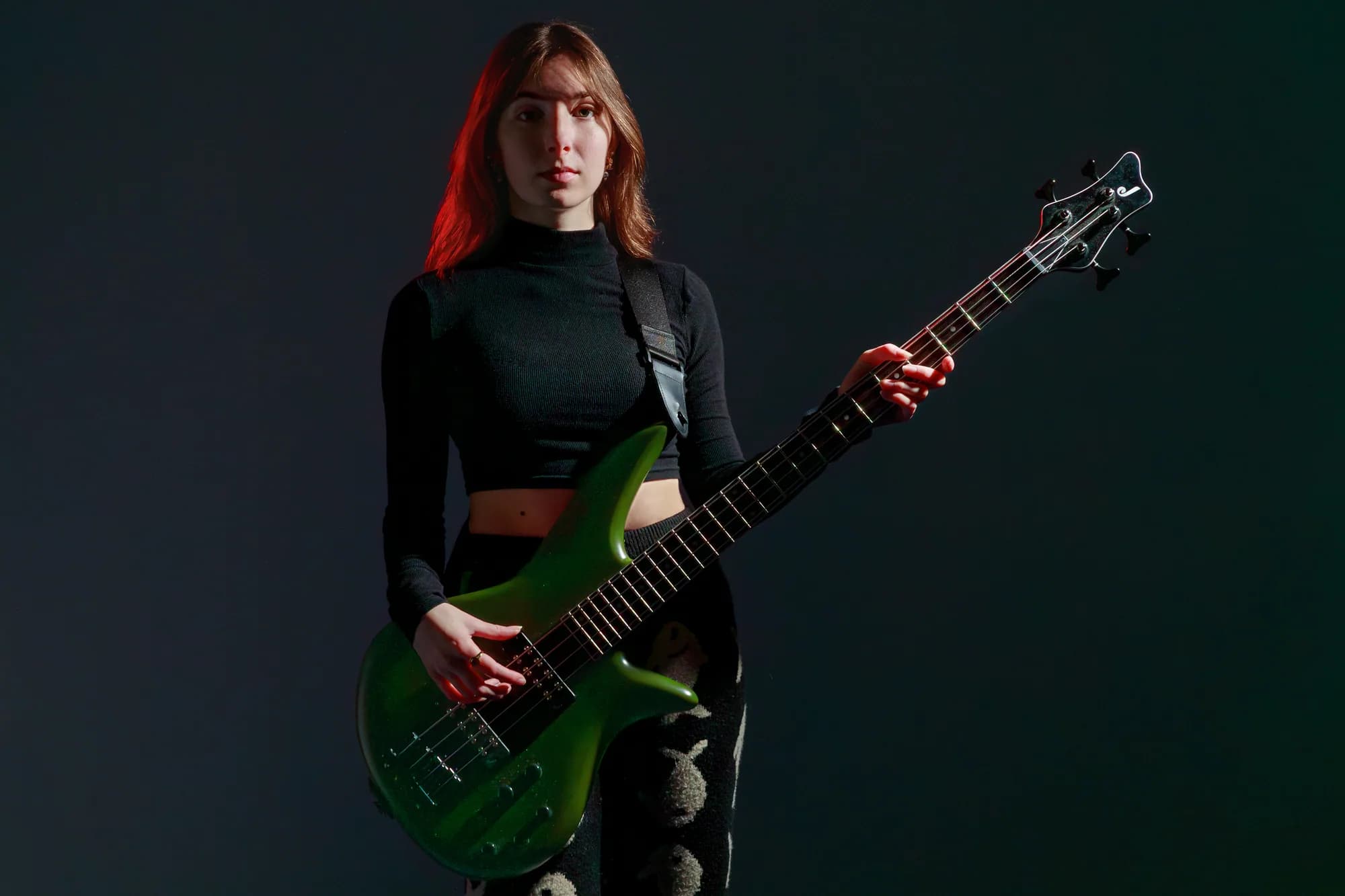 Tori Morley holding a green bass under red and green studio light.