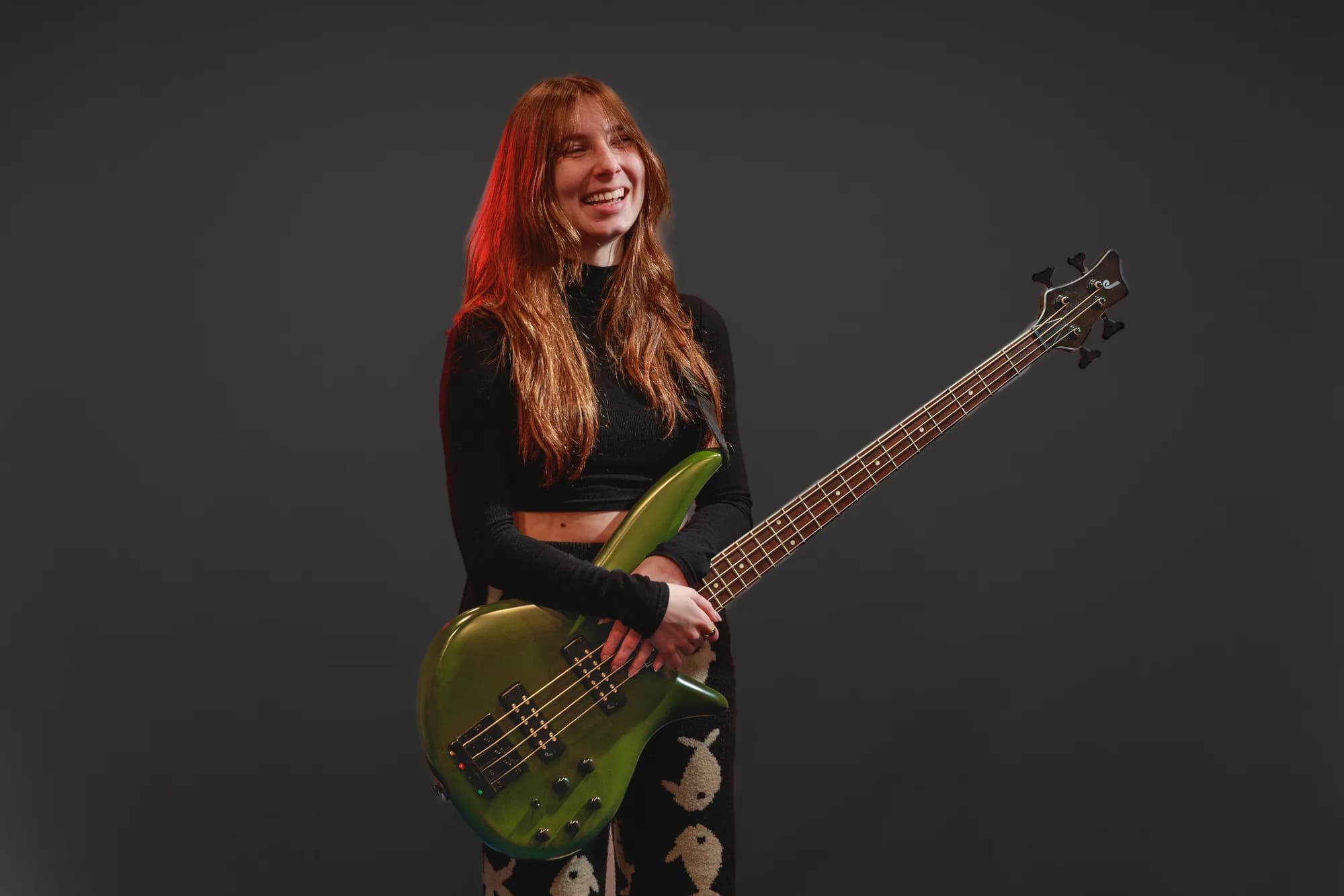 Tori Morley laughing with a green bass in studio.