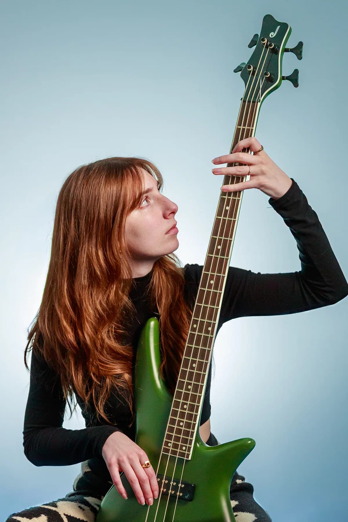 Tori Morley looking up along the neck of a green bass.