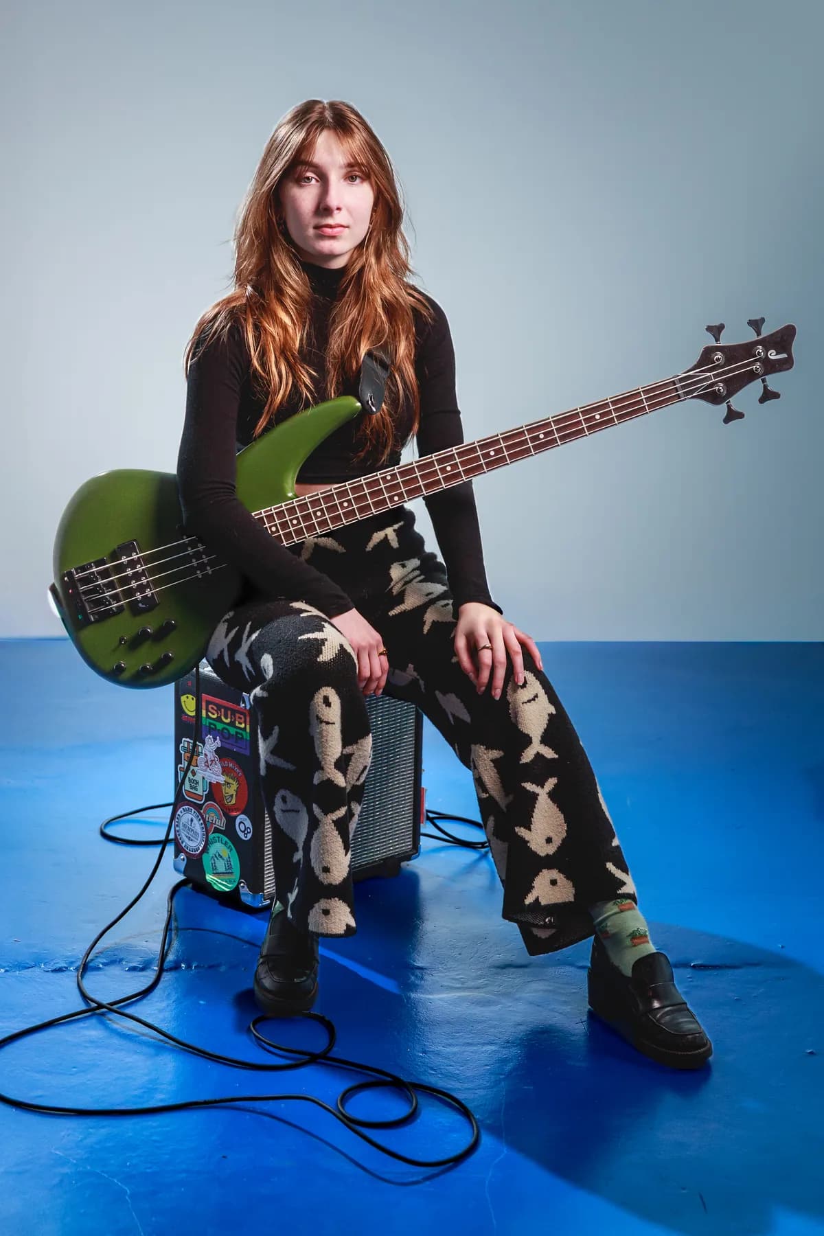 Tori Morley seated with a green bass in studio.